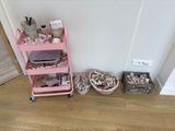 a pink cart that is next to a wall with a lot of stuff on it