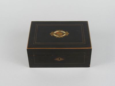 une petite boîte noire ornée d'un médaillon doré sur le couvercle