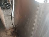 a silver refrigerator sitting in a dirty room with other appliances