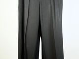 black pants hanging on a hanger against a white wall