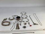 a lot of silver jewelry on a white surface