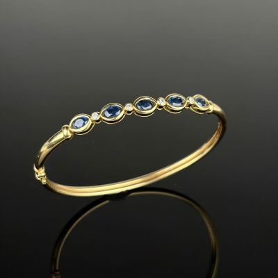 a yellow gold ring with blue sapphires and diamonds