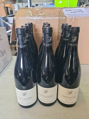 quatre bouteilles de vin sont posées sur une table devant un carton