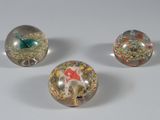 trois billes de verre empilées les unes sur les autres sur une surface blanche