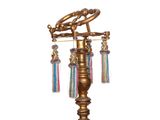 a gold colored lamp with tassels hanging from it