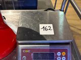 une bouilloire rouge posée sur une balance, sur une table
