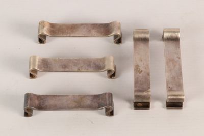 four pieces of silver metal on a white surface