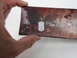 a person holding a piece of metal with a tag on it