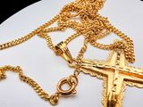 a gold cross and a gold chain on a white plate