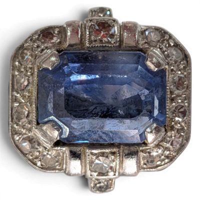 a close up of a blue sapphire and diamond broochle on a white background