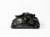 un gros plan d'un sac à main noir posé sur une surface blanche