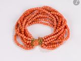 a close up of an orange beaded bracelet with a gold clasp
