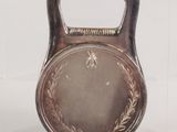 a silver kettle weight with a medal on it