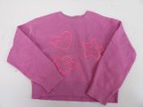 pink sweater with hearts and stars on it sitting on a white surface