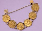 un gros plan d'un bracelet composé de pièces d'or sur fond violet