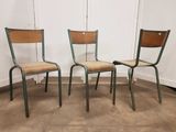 trois chaises dans une pièce aux murs blancs et au sol marron