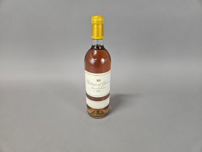 miniature bottle of wine with a yellow cap sitting on a gray surface