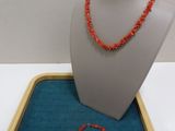 an orange beaded necklace and bracelet sitting on a blue tray