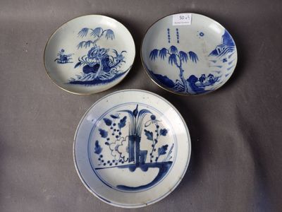 trois assiettes bleues et blanches ornées de motifs orientaux, posées sur une table