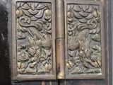 a close up of a metal door with a bird and flowers on it