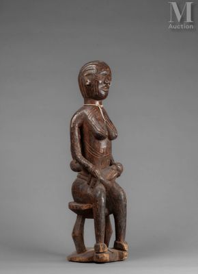a wooden statue of a woman sitting on a stool