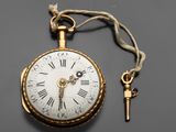 une montre de poche ancienne à laquelle est suspendue une clé, attachée à sa chaîne