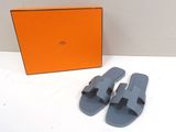 une boîte orange avec une paire de sandales grises à côté