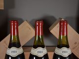 three bottles of wine sit in a wooden box on a table