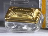 a small glass box with a gold lid next to a box with a silver lid