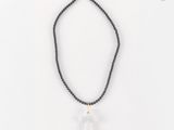 un collier de perles noires orné d'un pendule en quartz transparent