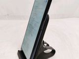 a close up of a cell phone on a stand on a white surface