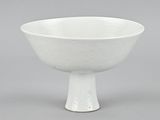 a white bowl with a pedestal base on a gray surface
