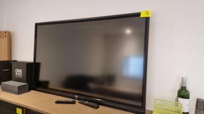 a flat screen tv sitting on top of a wooden shelf