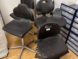 cinq chaises de bureau disposées dans une pièce, à côté d'une pile de cartons