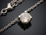 un collier de diamants suspendu à une chaîne, posé sur une surface noire