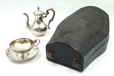 une théière en argent et une tasse en argent posées sur une table blanche