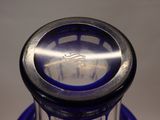 a blue glass bottle with a silver top on a table