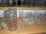 des bouteilles et des verres posés sur une étagère, dans une pièce où une étagère est remplie de verres à vin