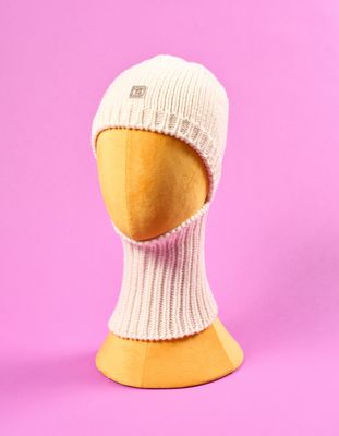 un bonnet blanc en tricot sur une tête de mannequin, sur fond rose