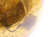 a gold ball with a hole in it on a white surface