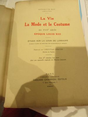 un livre ouvert sur une table, avec des feuilles de papier à côté