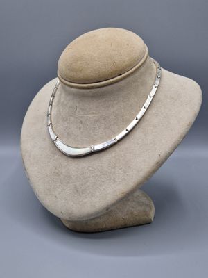un mannequin blanc sur lequel est posé un collier en argent
