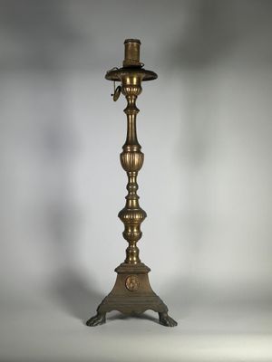 un bougeoir ancien en laiton surmonté d'une bougie