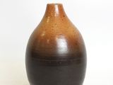 a brown and black vase sitting on a white surface
