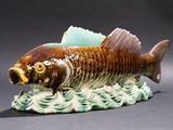 a ceramic fish that is sitting on top of a wave