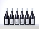 six bottles of red wine lined up in a row on a table