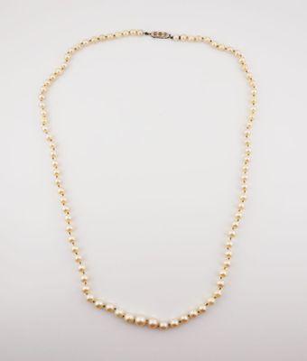 a gold beaded necklace with a single pearl bea
