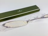 a silver spoon and a green box on a white surface