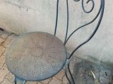 a metal chair sitting on the sidewalk next to a wall