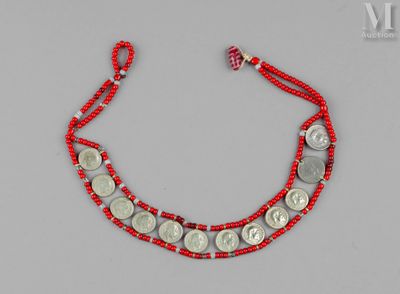 un gros plan sur un bracelet en ficelle rouge orné de pièces de monnaie